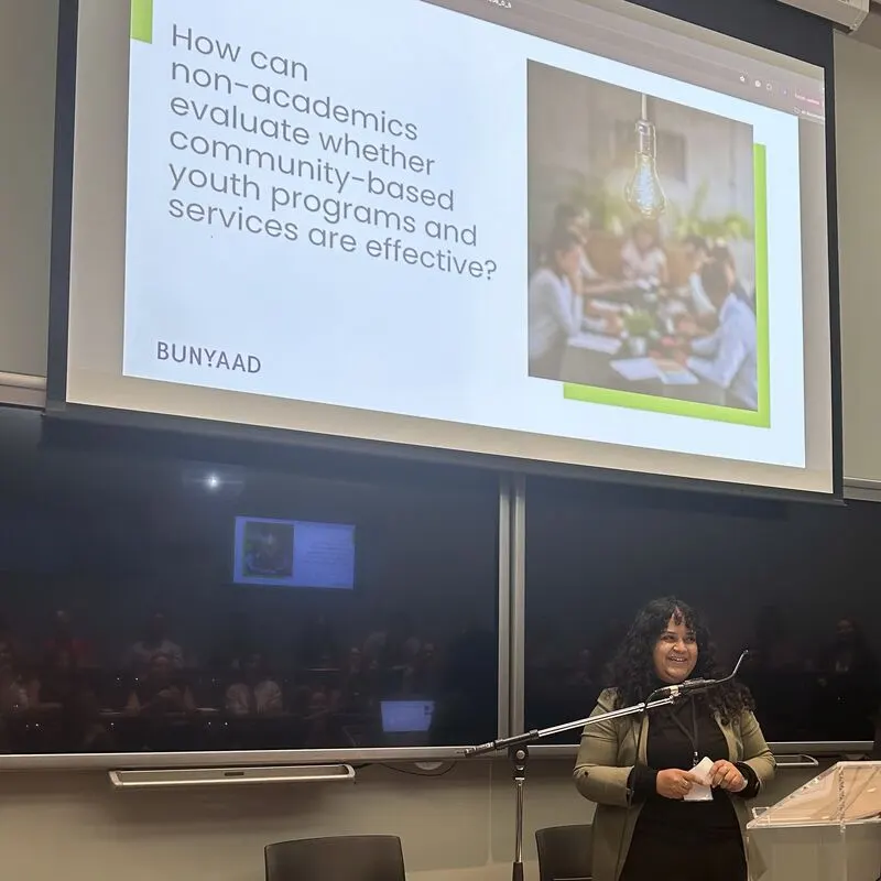 Sanchita presenting below a slide about evaluating youth programs