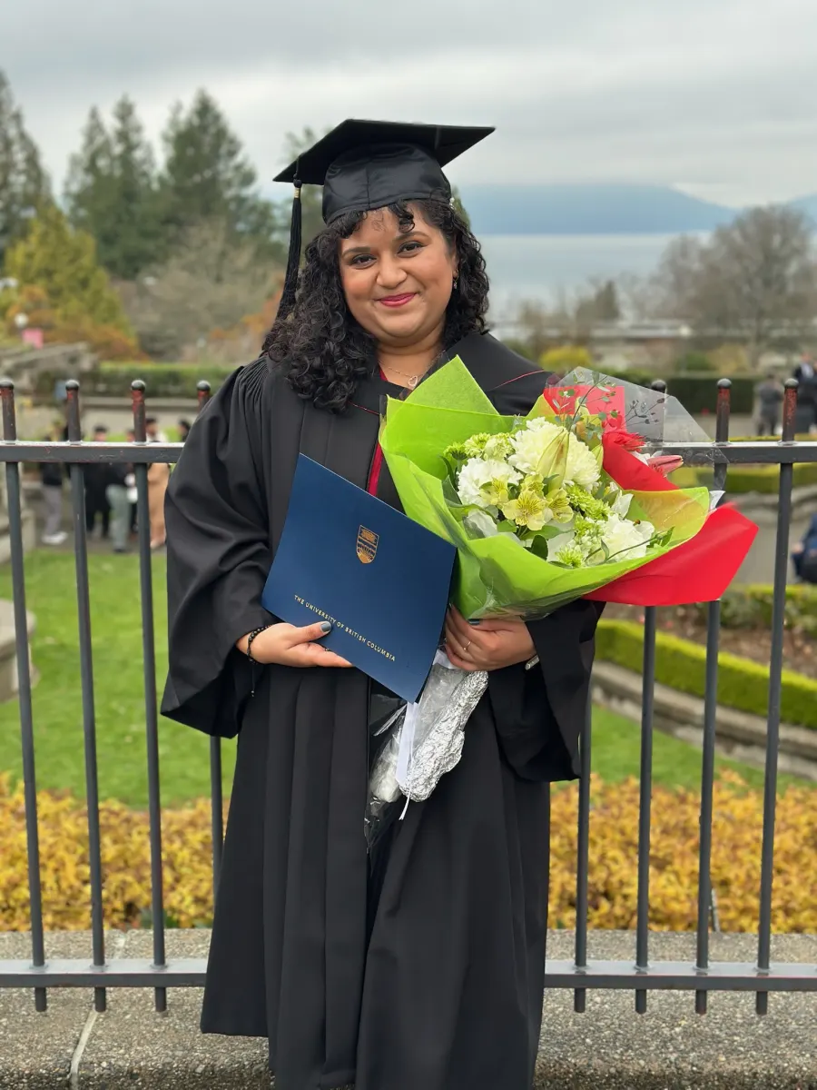 Sanchita in her graduation gown holding her UBC degree and a bouquet